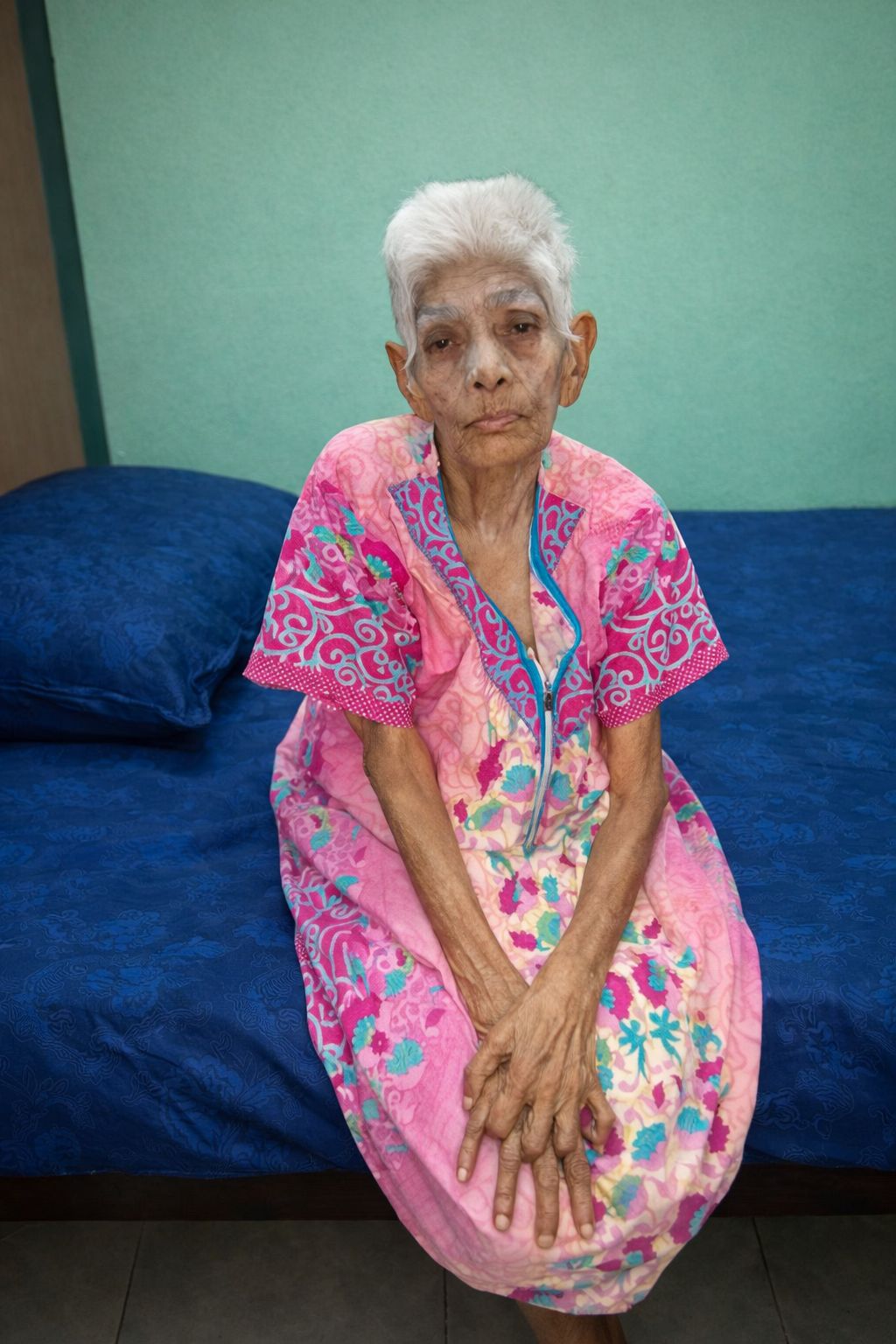 Elderly resident seated comfortably in the care home common area