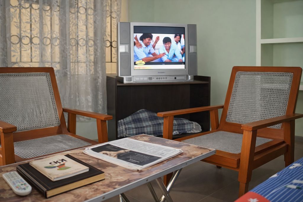 Comfortable TV lounge with cushioned armchairs and wall-mounted television for residents