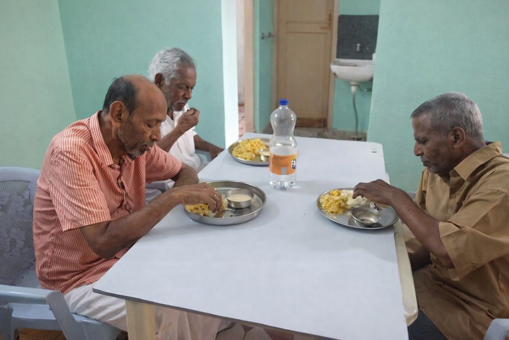 Residents sharing a meal together at the communal dining table with staff assistance